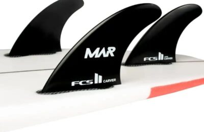 Close-up of black MAR FCS II surfboard fins mounted on a white surfboard.